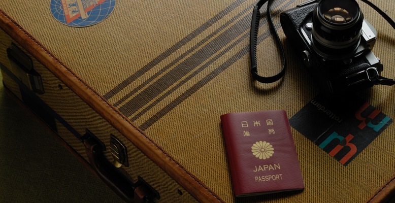 パスポートとカメラが旅行鞄の上に置かれている